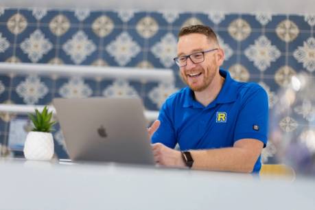 An admission counselor in a blue Rollins polo video chats with a student.