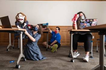 Students hold puppets during an online workshop. 