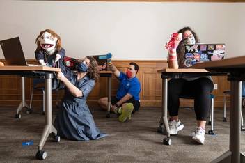 Students hold puppets during an online workshop.