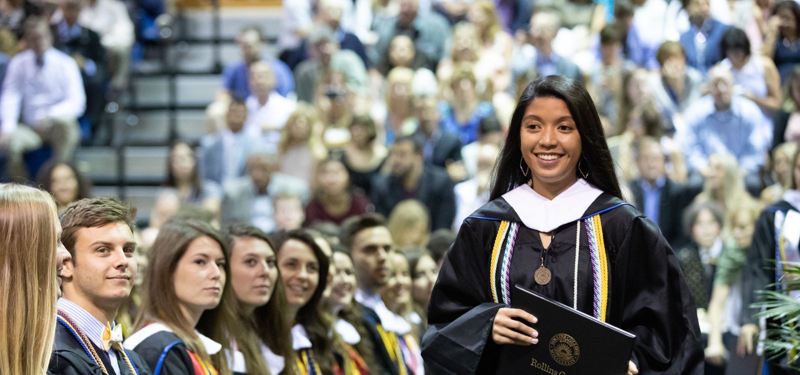 Rollins walking in their cap and gown at Commencement