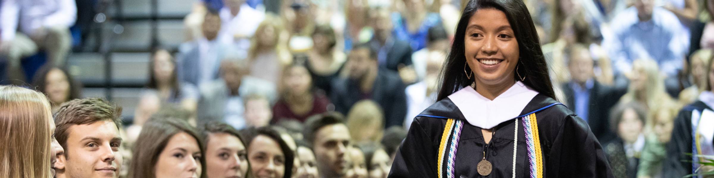 Rollins walking in their cap and gown at Commencement