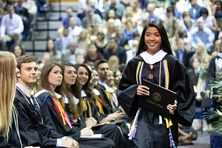 A student smiles after receiving her college diploma.