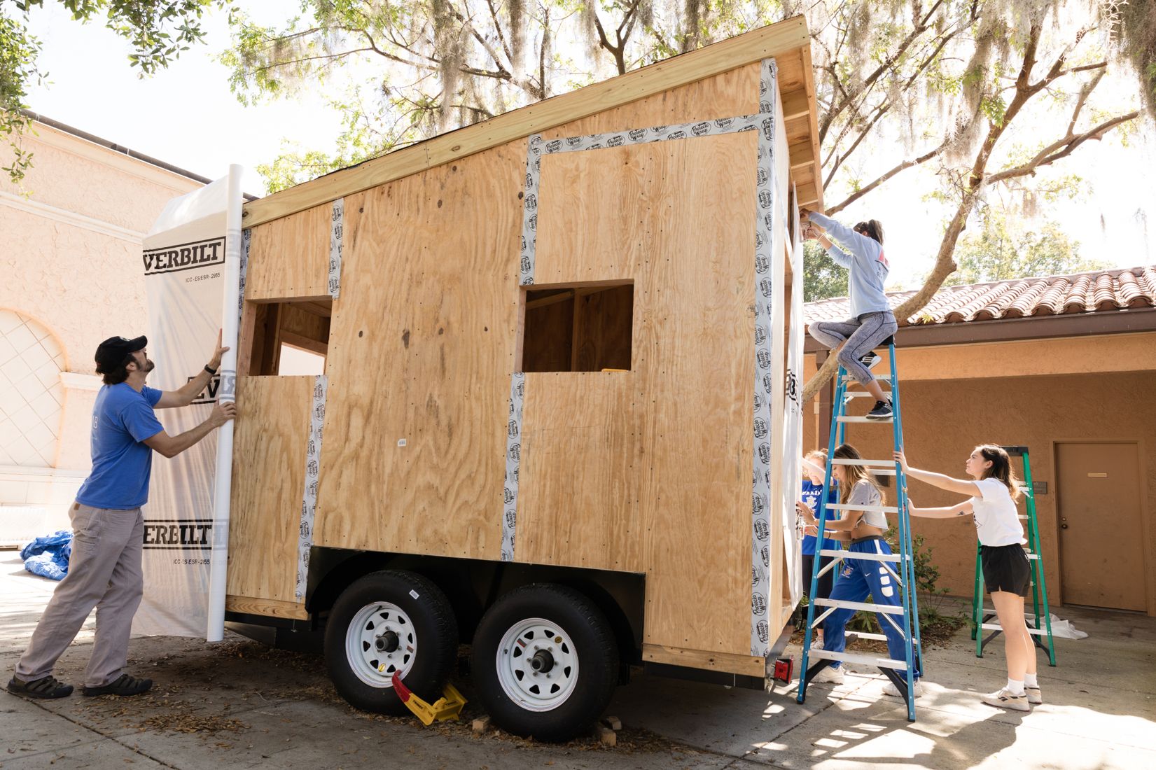 Joshua Almond and his students working to weatherproof the exterior of a tiny home class project.