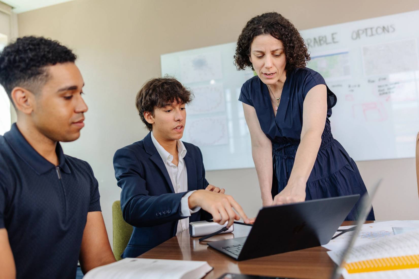 Instructor with two students looking at a lap top computer