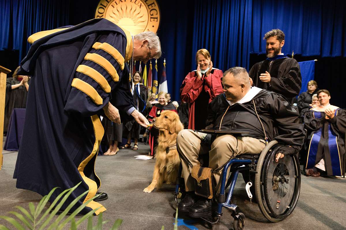President Cornwell gives a dog a treat on stage.