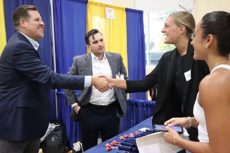 Students shaking hands with employer at job fair