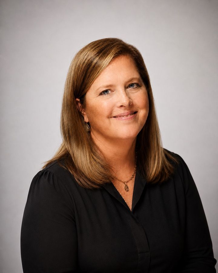 Professional headshot of a smiling Trish Moser against a neutral background.
