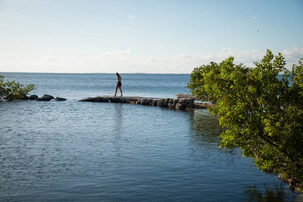 Student walking out on a sandbar over the water in the Everglades.