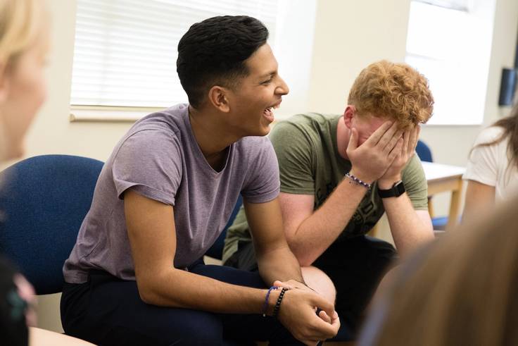 A college student laughs along with classmates in a first-year class.