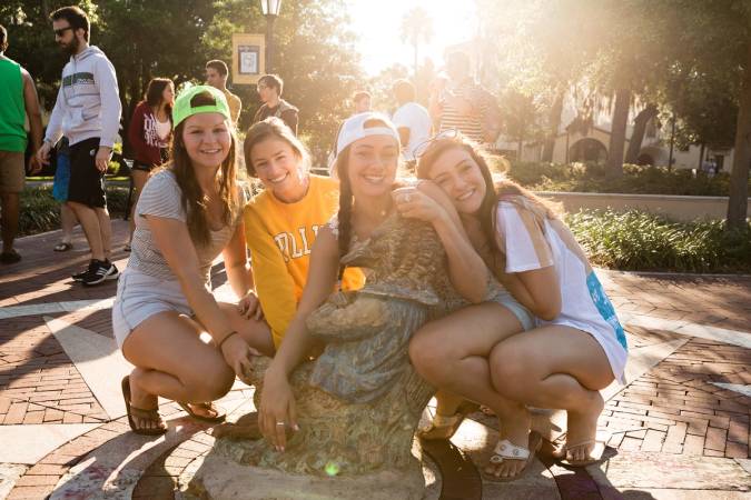 Four students pose with the fox statue on Tars Plaza