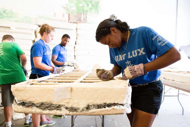 A college student helping to re-cover a mattress during SPARC day.