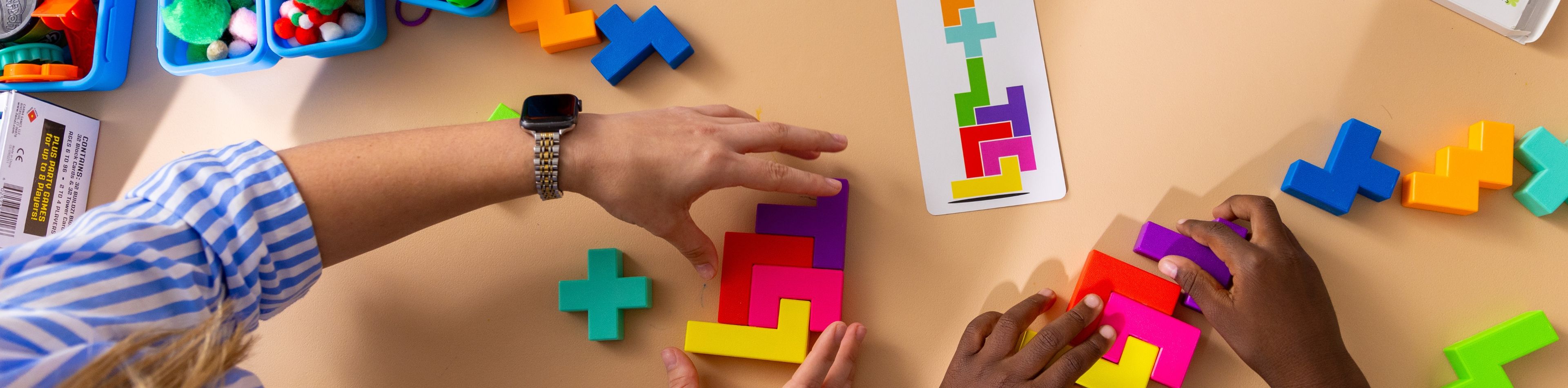 A behavior analyst takes notes while observing a student playing with building blocks.