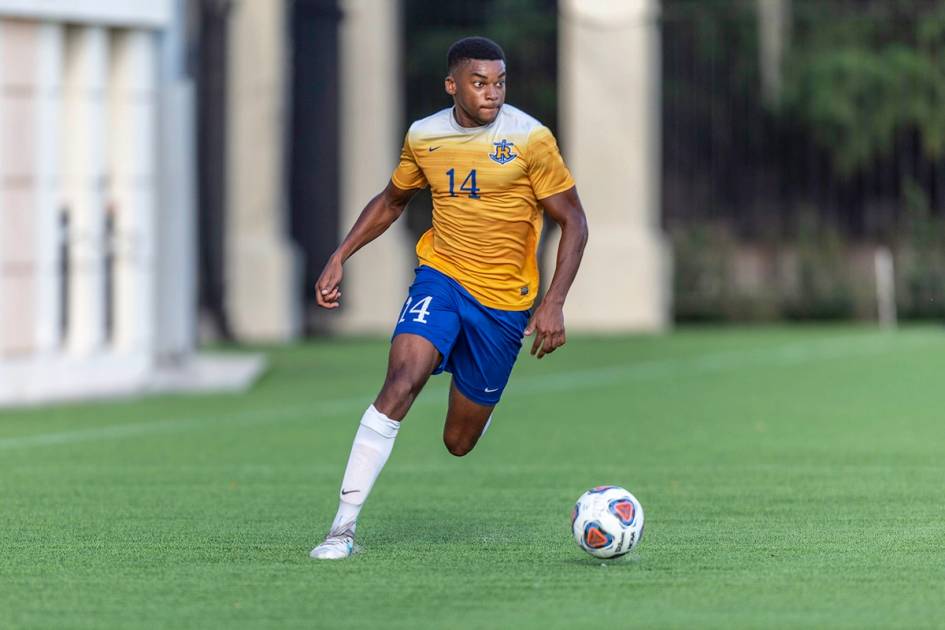 A soccer player dribbles down the wing.