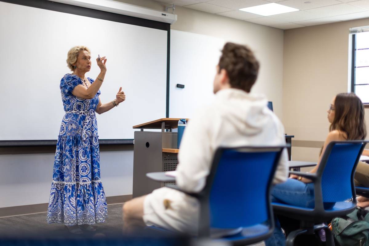 Women in Finance Academic Director Anca M. Voicu   lecturing to seated students in a classroom with projection screen.