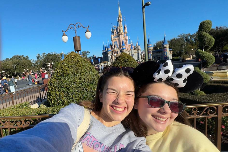 Two visitors take a cheerful selfie in front of Cinderella Castle.