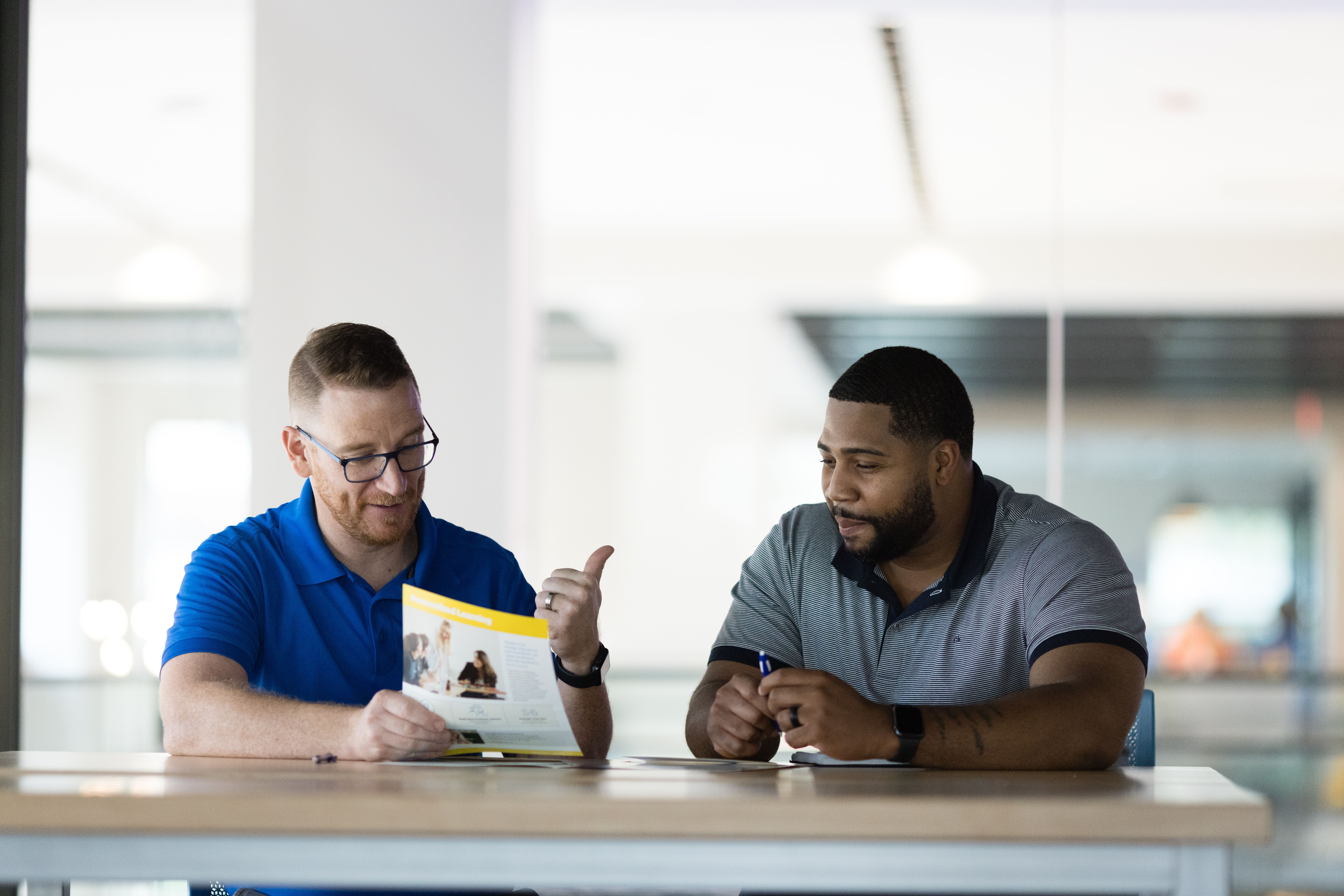 A Rollins counselor in a blue polo shirt meets one on one with a prospective student.