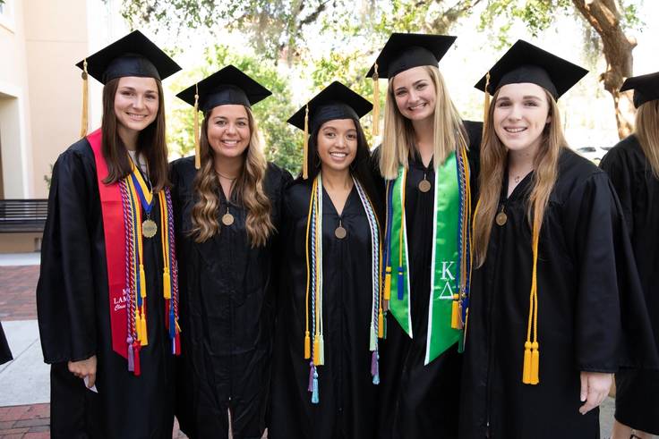 Students in commencement attire pose for a photo.
