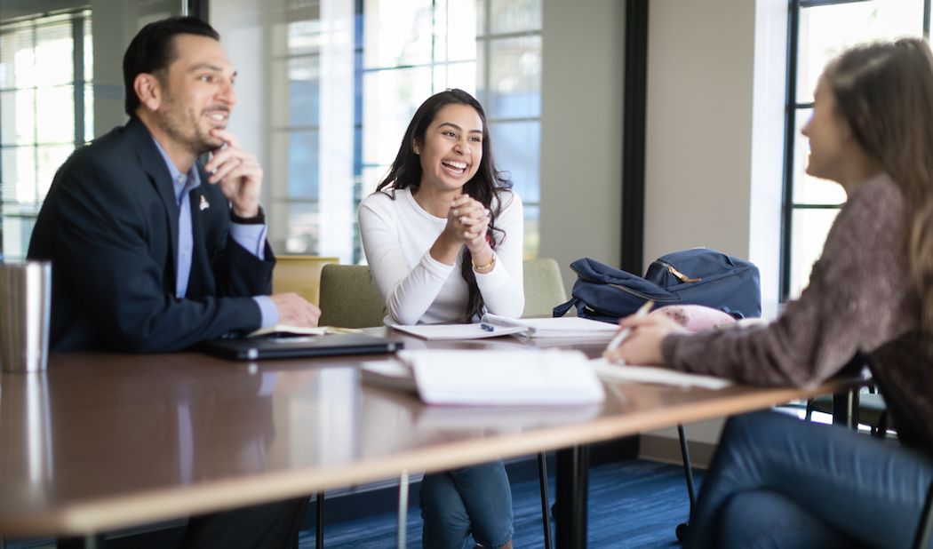 A business advisor meets with a pair of students.