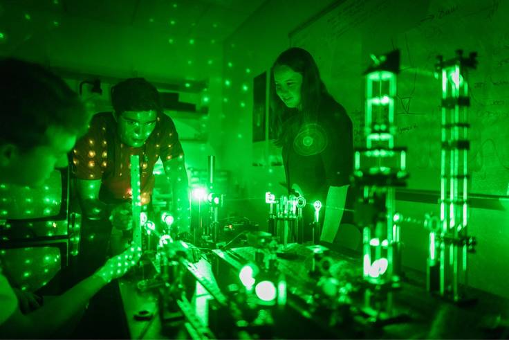 Physics students and professor work with lasers. 