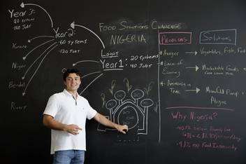 Colin Kelly ’19 ’21MBA in front of a chalkboard displaying his business plan for his startup venture.