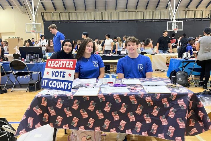 Irteza ’27 volunteers at a Democracy Project voter registration table at a crowded community event.