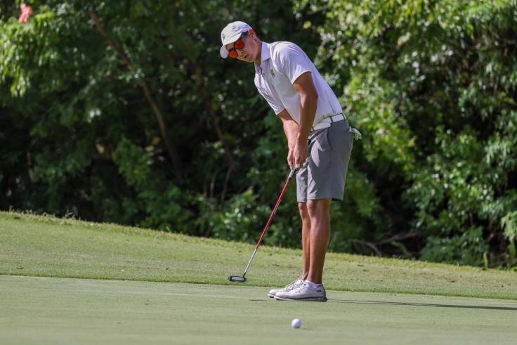 Member of the Rollins men’s golf team putting on the green.