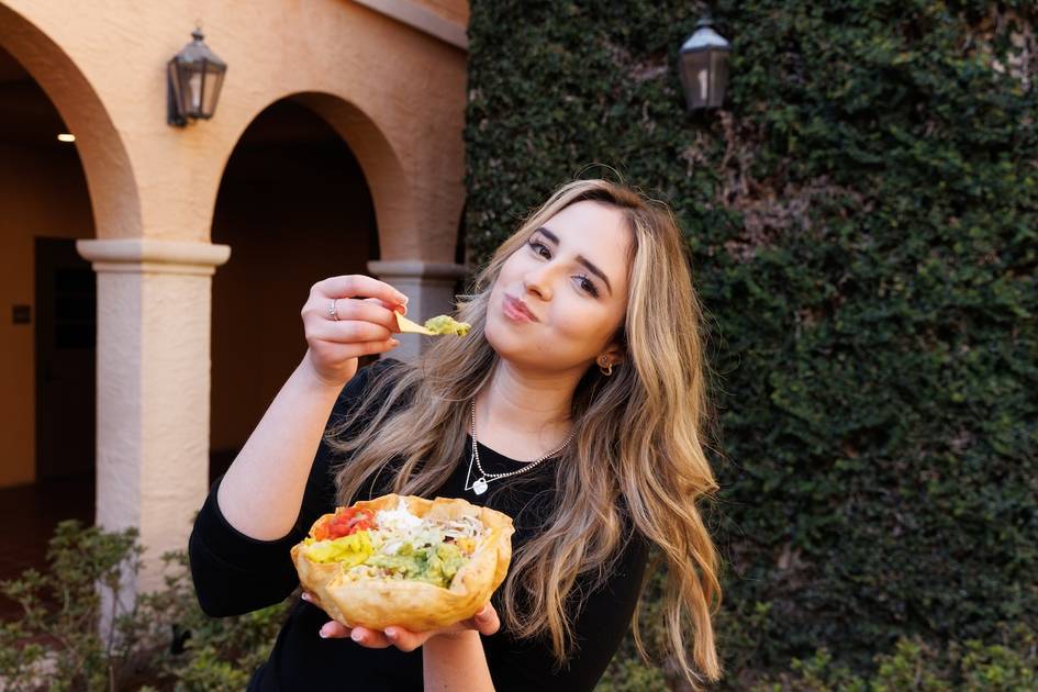 A student poses with a burrito bowl on campus.