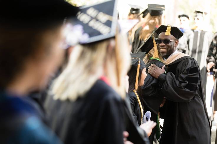 A professor hugs students before commencement.