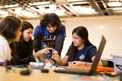 Students build modular robots next to a computer.