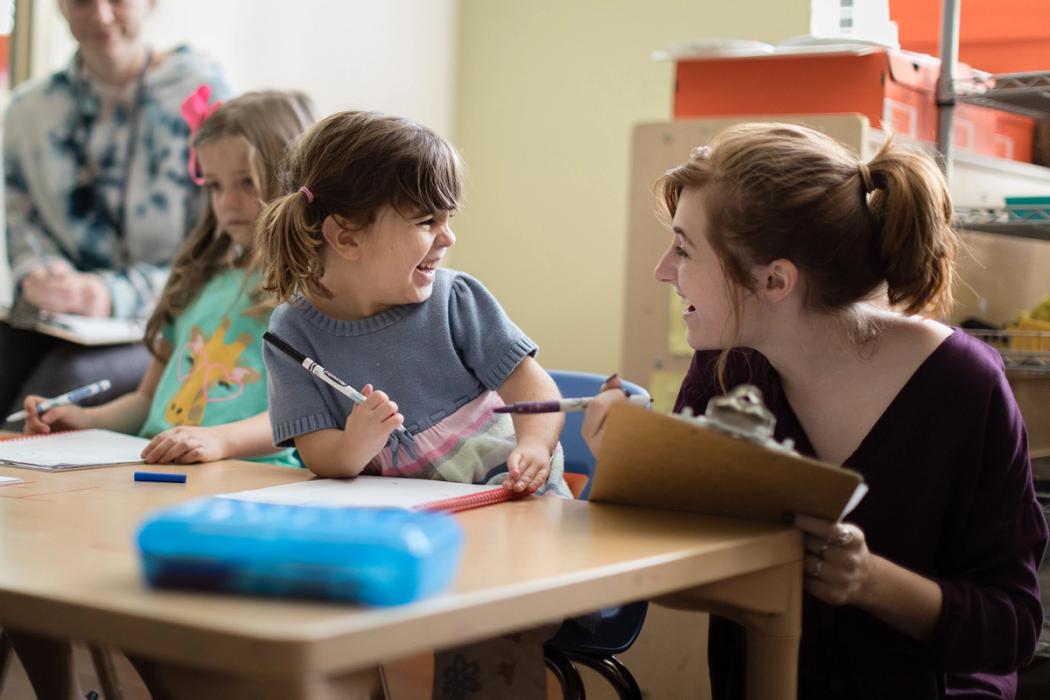 A child and a teacher laugh together.