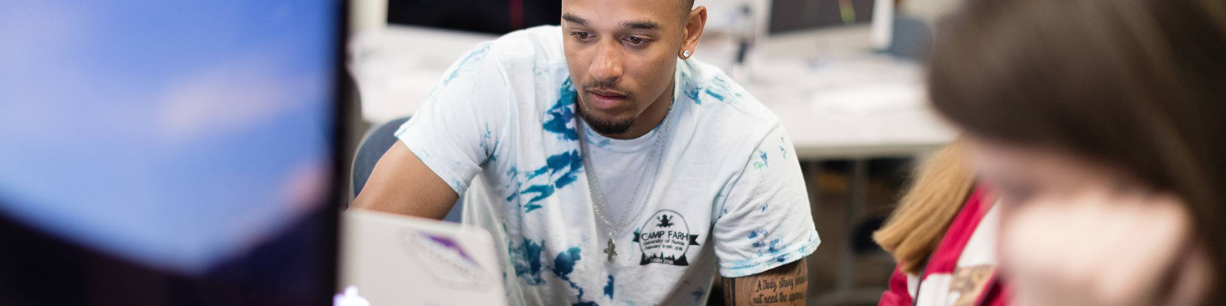Critical media professor interacts with two students in class.