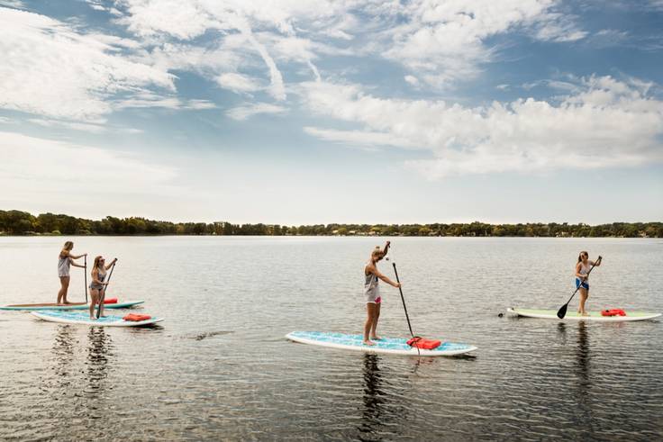 A group of students paddleboard on Lake Virginia.