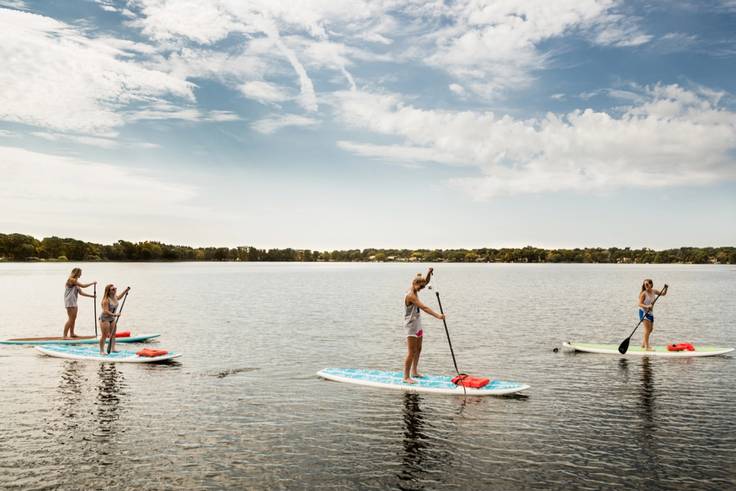 A group of four students paddle boards on Lake Virginia.