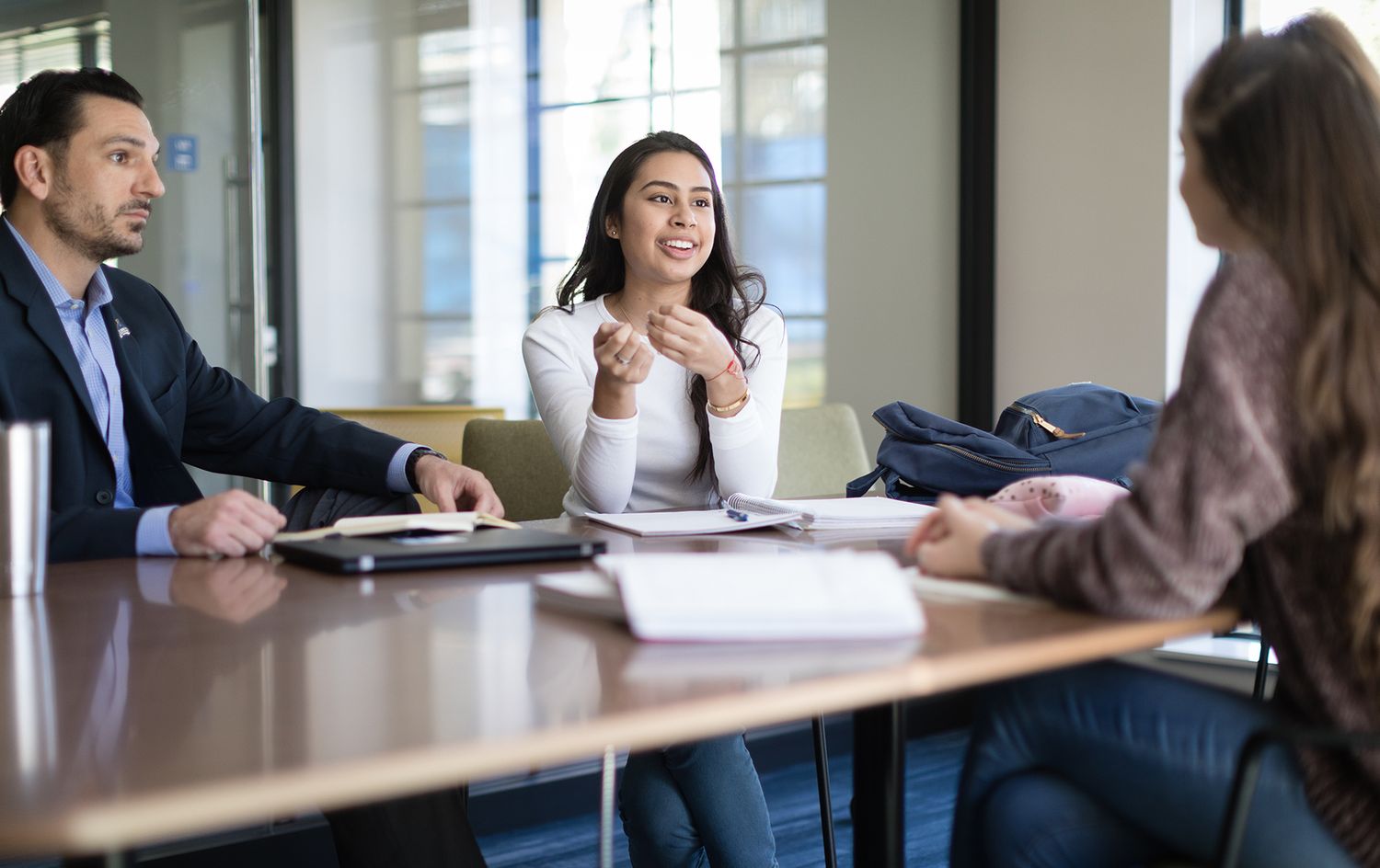 Two students chat with a Rollins professor