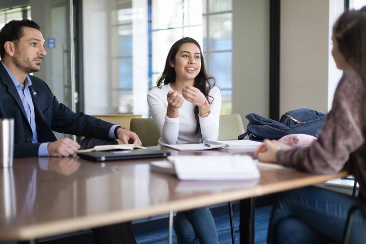 Two students chat with a Rollins professor