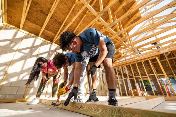 Students hammer wooden boards while constructing a house frame together on Thad & Polly Acts of Kindness Day