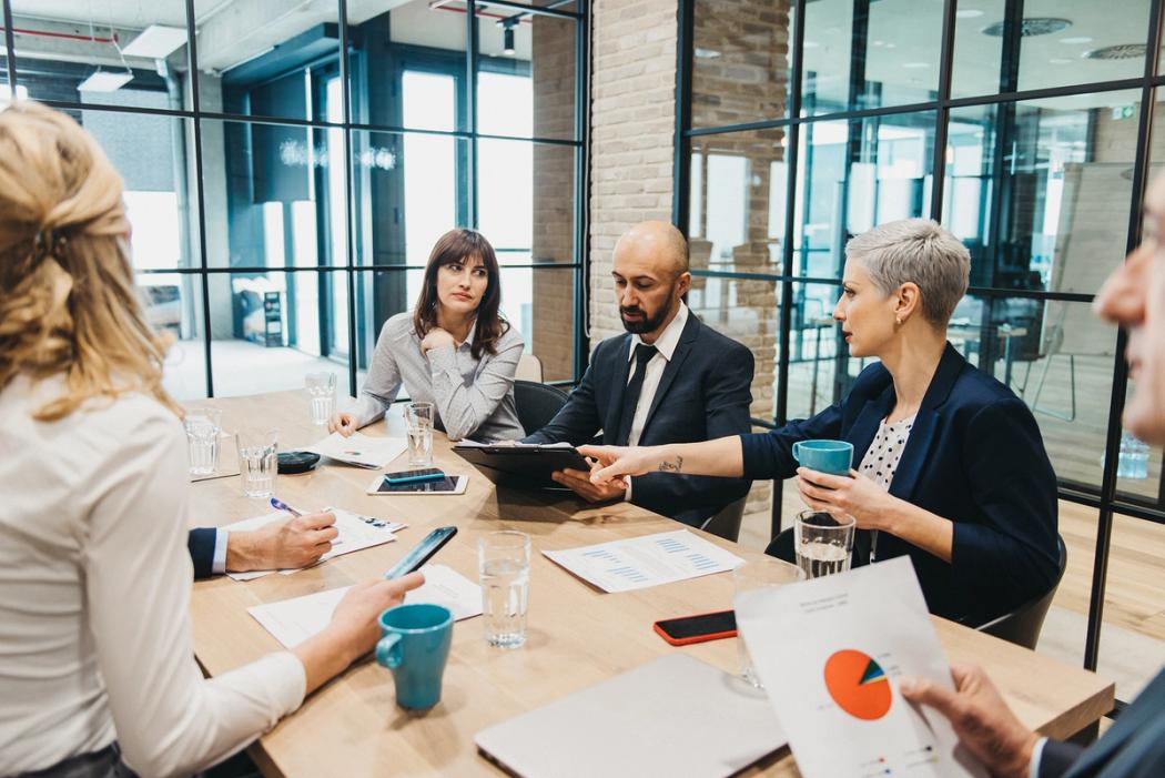 A communications director leads a meeting with a group of colleagues.