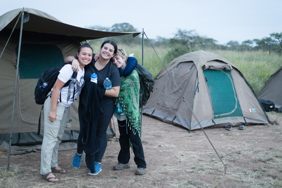 Three students posing for a photo outside of their tents in Tanzania.