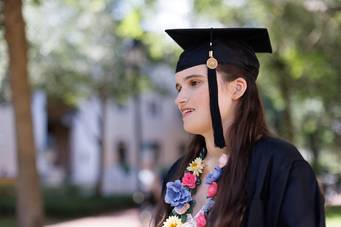 A college student poses in graduation regalia on the Rollins College campus.