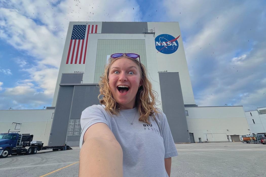 A student takes a selfie in front of the vehicle assembly building at Kennedy Space Center.