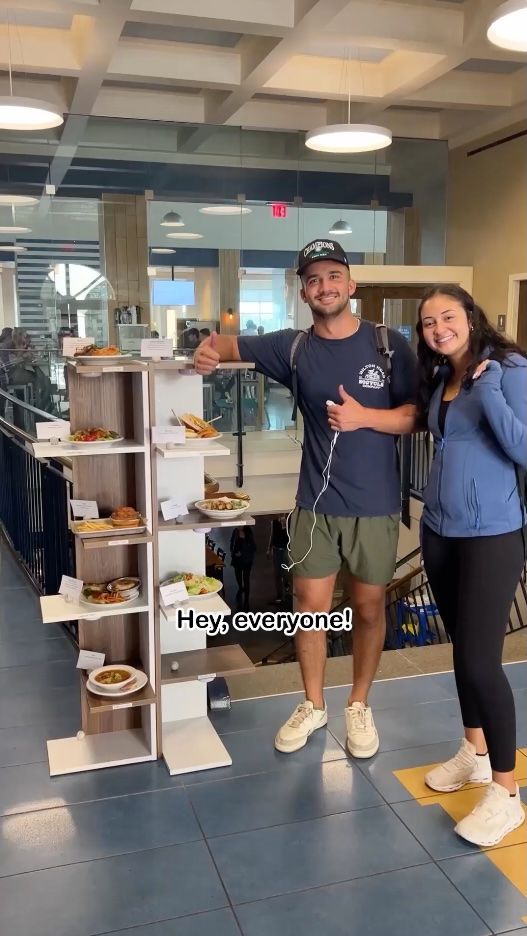 Two students standing in front of the Rollins dining hall, Cornell Campus Center.
