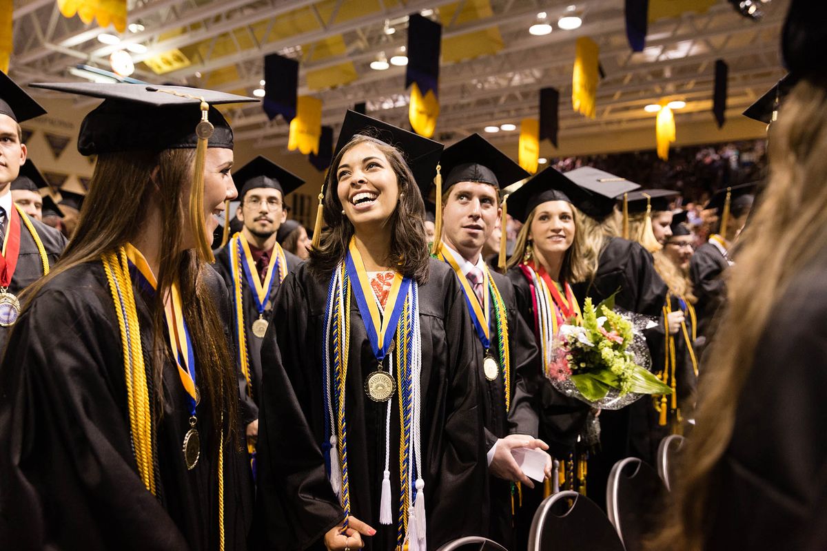 High achieving students, with medals and many ropes around their necks, smile up to their families at the commencement ceremony