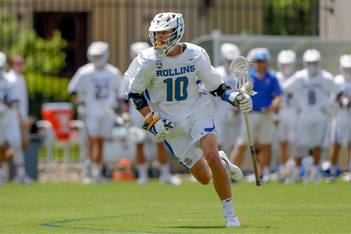 Greg Taicher fully dressed in his Rollins Lacrosse uniform running on the field.
