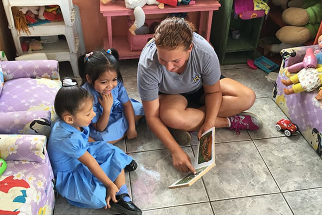 Rollins social entrepreneurship student reads a book to children.