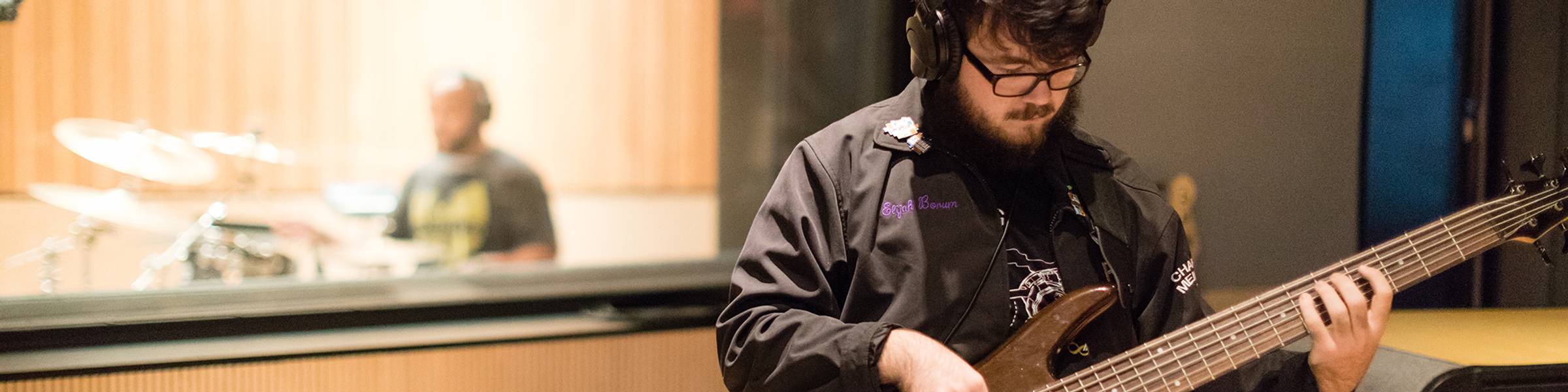 A Rollins student plays bass in a music studio.