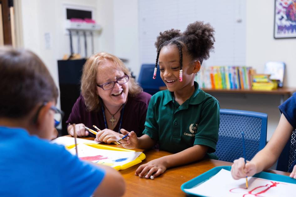 A teacher works with a group of young school children.