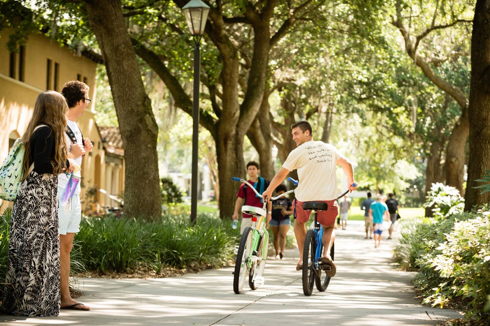 Rollins student riding bicycles on campus
