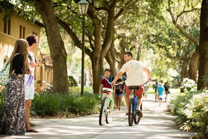 Rollins student riding bicycles on campus