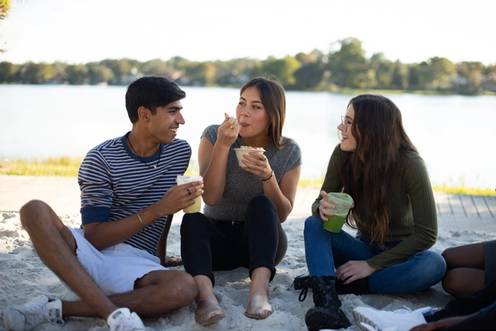 Three students sitting and enjoying a meal by Lake Virginia. 