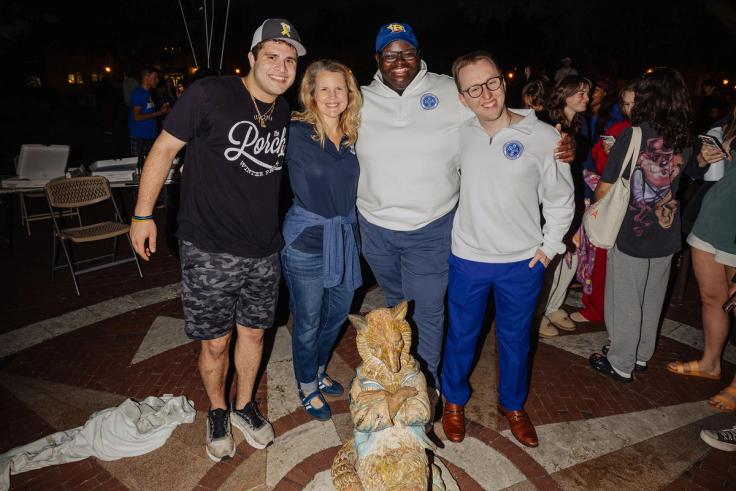 President Barnett and student leaders from SGA smiling as they put the Fox statue in place